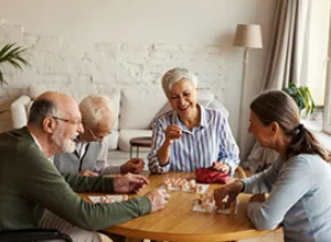 Seniors engaging in a cheerful game at a table, promoting social interaction and community in a senior living environment.